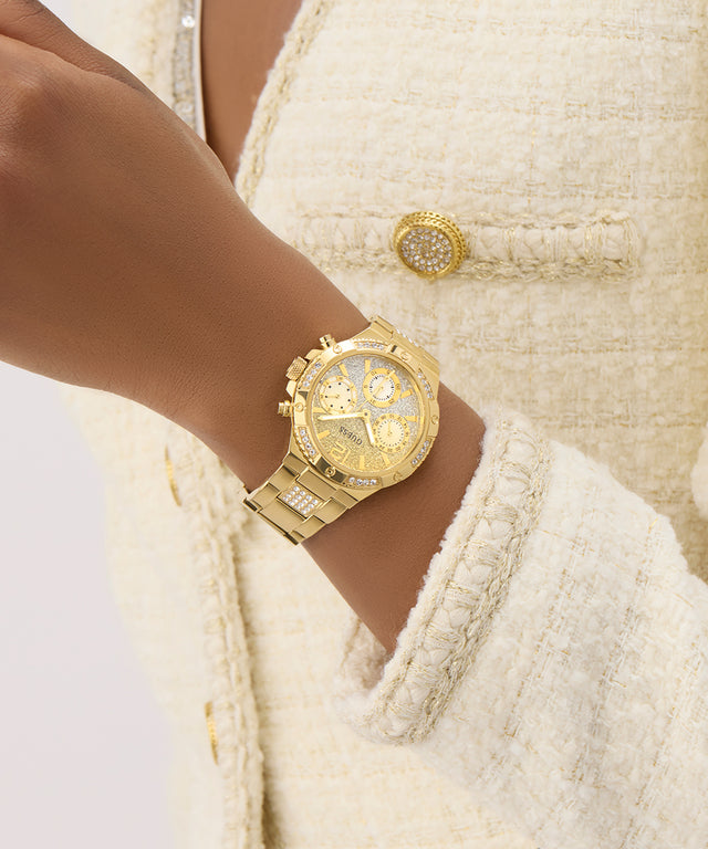 GUESS Ladies Gold Tone Multi-function Watch on a wrist with a textured cream-colored jacket
