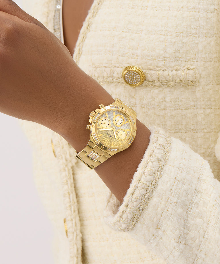 GUESS Ladies Gold Tone Multi-function Watch on a wrist with a textured cream-colored jacket