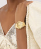 GUESS Ladies Gold Tone Multi-function Watch on a person wearing a sparkly top and white jacket.