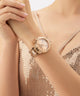 GUESS Ladies Rose Gold Tone Multi-function Watch on a wrist with a sparkly background