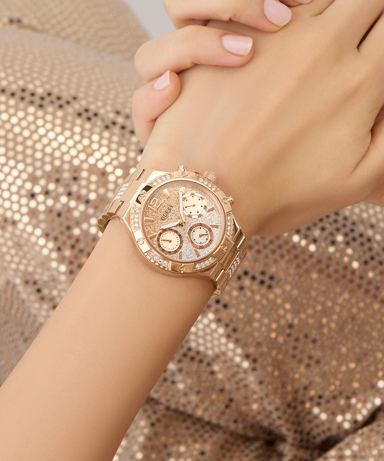 Rose gold watch on a wrist with a glittery background