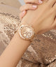 Rose gold watch on a wrist with a glittery background