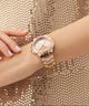 Rose gold watch on a wrist with a glittery background