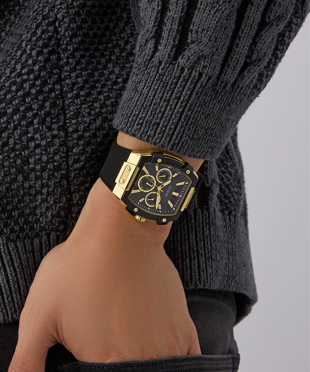 Gold watch on a wrist with a gray sweater GUESS Mens Black Gold Tone Multi-function Watch GW0956G2