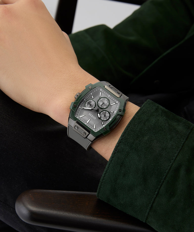 Close-up of a person wearing a green and silver watch on a dark background GUESS Mens Grey Gunmetal Multi-function Watch