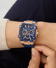Blue and rose gold Guess watch on a wrist with a blurred background GUESS Mens Blue Rose Gold Tone Multi-function Watch GW0956G4