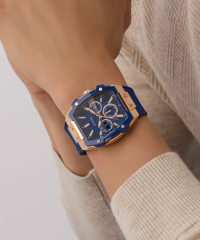GUESS watch with blue and rose gold design on a wrist, wearing a beige sweater.