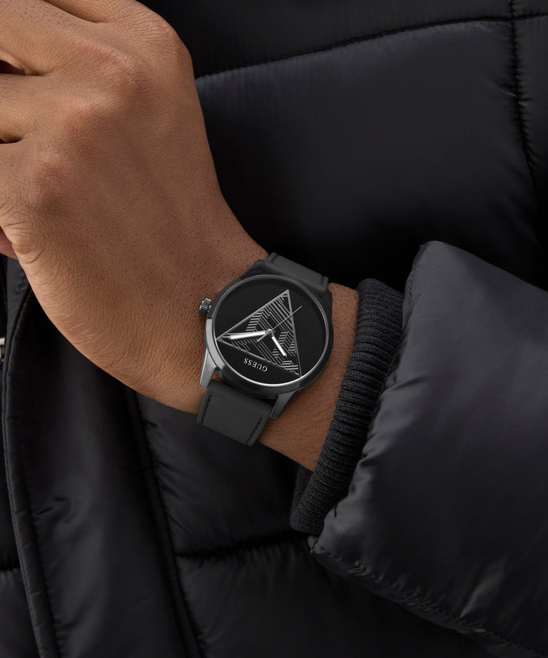 Person wearing a black GUESS Mens Black Analog Watch with a geometric design on a black jacket.