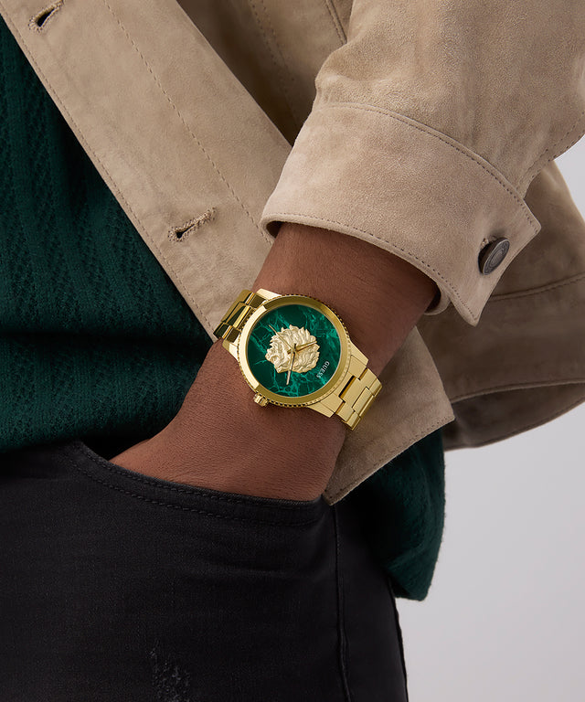 GUESS Mens Gold Tone Analog Watch with green face on wrist against a neutral background