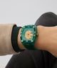 GUESS Mens Green Analog Watch with gold lion emblem on wrist against a neutral background