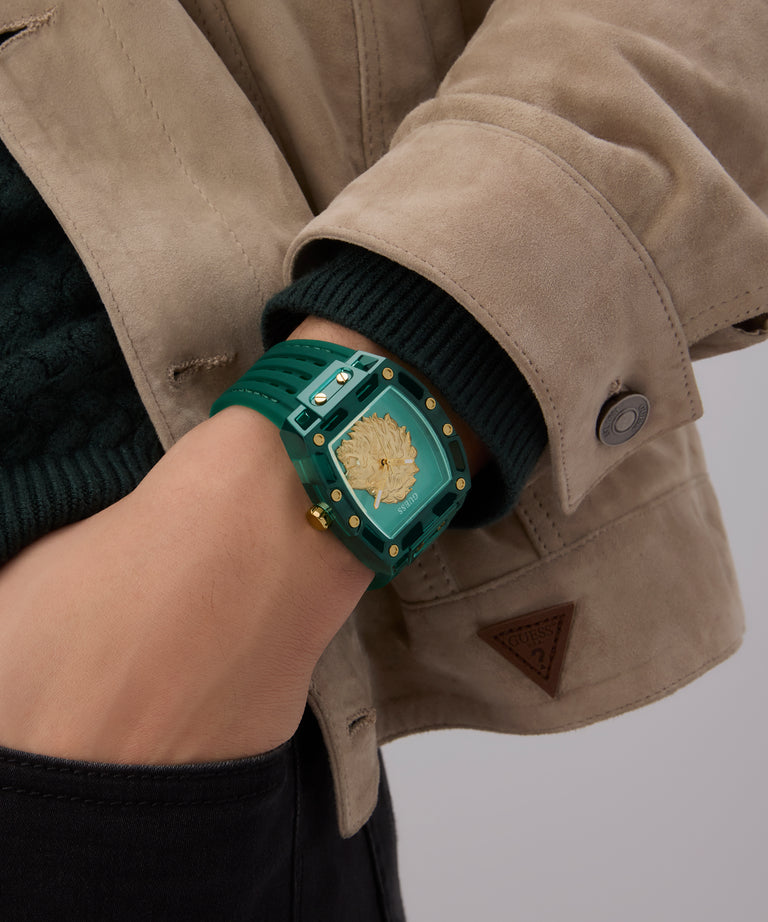 Person wearing a GUESS Mens Green Analog Watch with decorative elements on a plain background