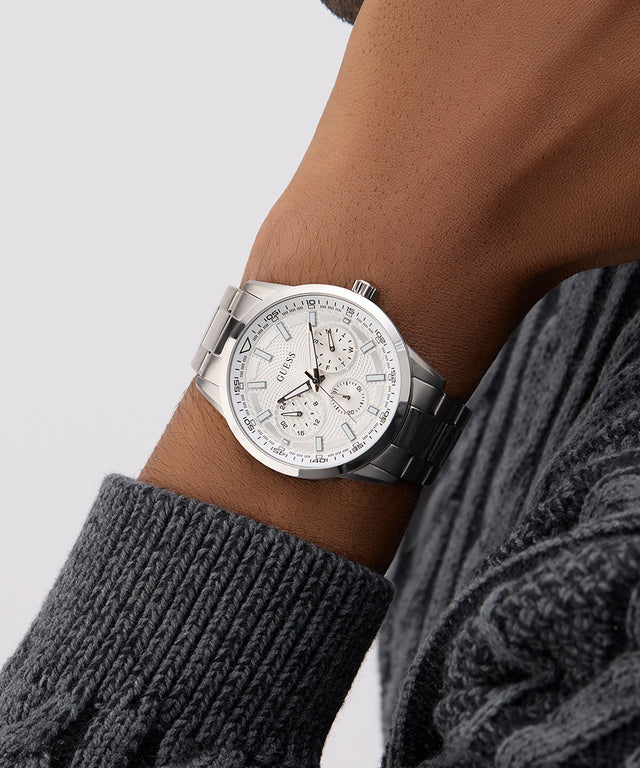 GUESS Mens Silver Tone Multi-function Watch on a wrist with a gray sweater sleeve against a light gray background