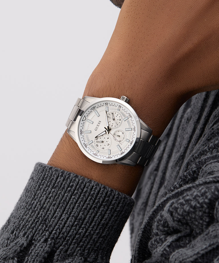 GUESS Mens Silver Tone Multi-function Watch on a wrist with a gray sweater sleeve against a light gray background