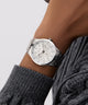 GUESS Mens Silver Tone Multi-function Watch on a wrist with a gray sweater sleeve against a light gray background