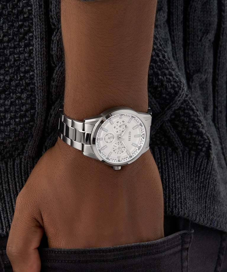 GUESS Mens Silver Tone Multi-function Watch on a wrist with a dark textured background