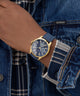 Person wearing a blue watch with gold accents on a denim jacket. GUESS Mens Blue Gold Tone Multi-function Watch GW0964G2