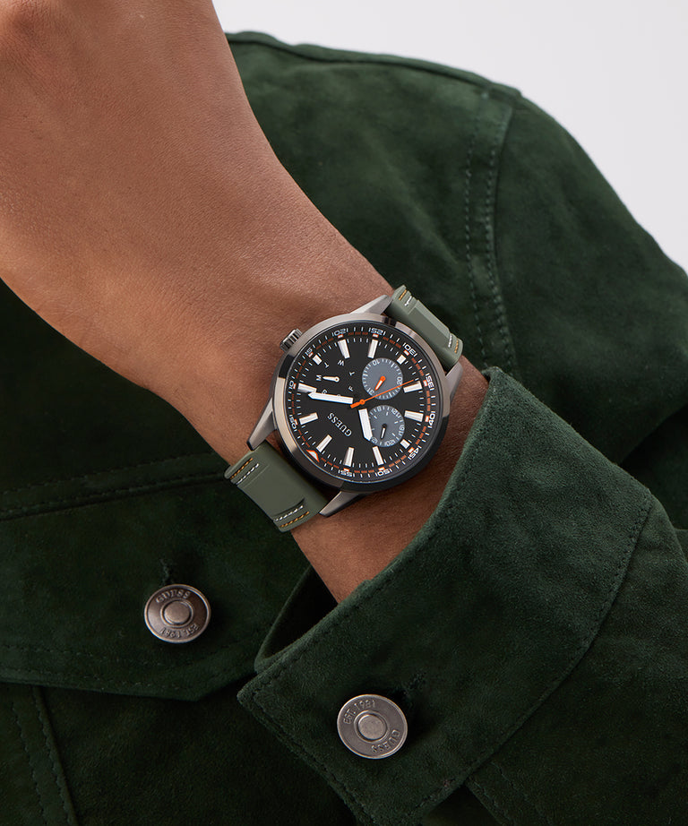 Person wearing a dark green watch on a matching jacket against a neutral background GW0964G3