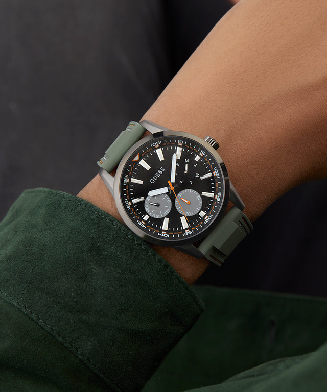 Person wearing a green wristwatch with a dark face on a dark background GW0964G3