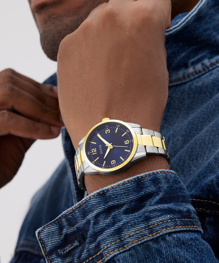 Close-up of a wrist wearing a two-tone watch with a blue face and gold accents. GW0965G4