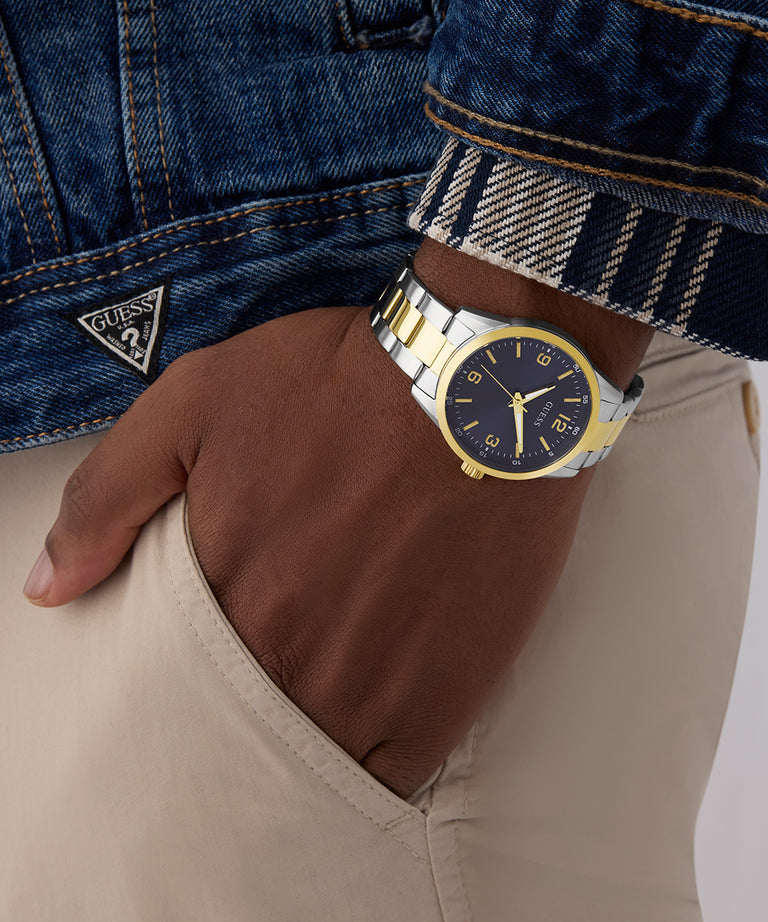 Gold and silver watch on a wrist with a denim jacket and beige pants. GW0965G4