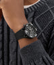Black watch on a wrist with a textured gray sweater