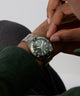 Person adjusting a GUESS Mens Gunmetal Analog Watch on their wrist with a neutral background