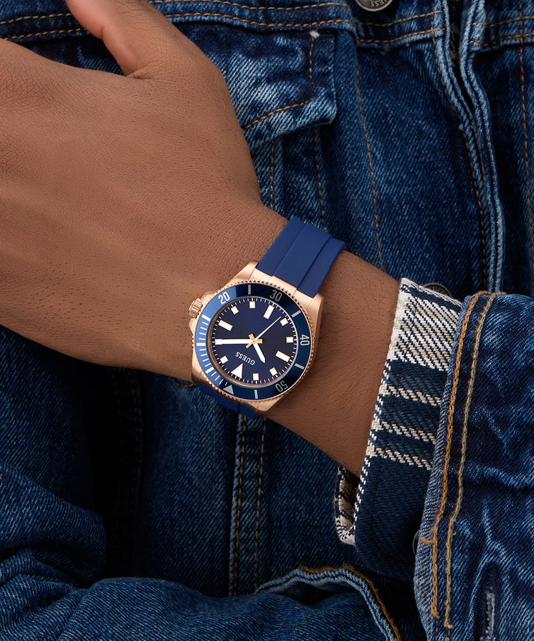 Hand wearing a blue watch with rose gold case on denim sleeve GW0969G3