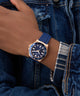 Hand wearing a blue watch with rose gold case on denim sleeve GW0969G3