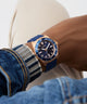 Blue watch with gold case on a wrist, wearing denim jeans. GW0969G3