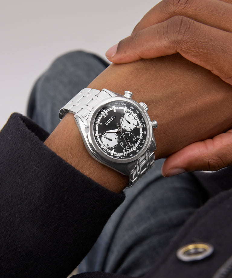 Silver GUESS Mens Silver Tone Multi-function Watch on a person's wrist with a blurred background