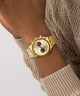 GUESS Mens Gold Tone Multi-function Watch on a wrist with a neutral background