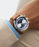 Wrist wearing a Guess watch with a brown strap and blue face. GW0972G1