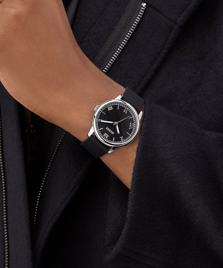 Black wristwatch on a person's wrist with a dark background
