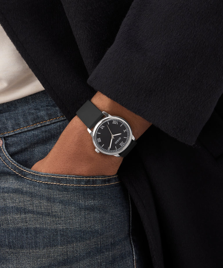 Person wearing a black watch with a dark strap on a blurred background