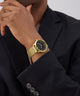 GUESS Mens Gold Tone Analog Watch on a person's wrist with a black suit jacket