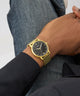 GUESS Mens Gold Tone Analog Watch on a wrist with a neutral background