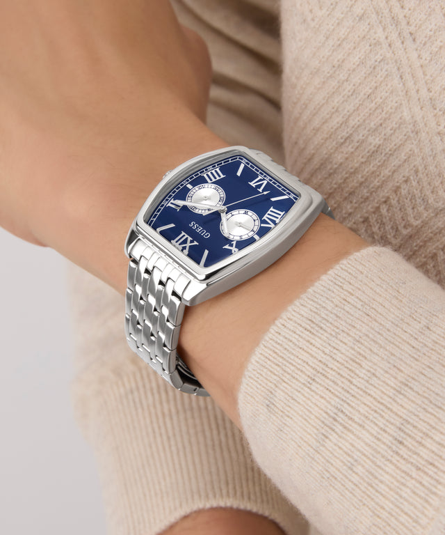 GUESS Mens Silver Tone Multi-function Watch watch with a blue face on a wrist, wearing a beige sweater.
