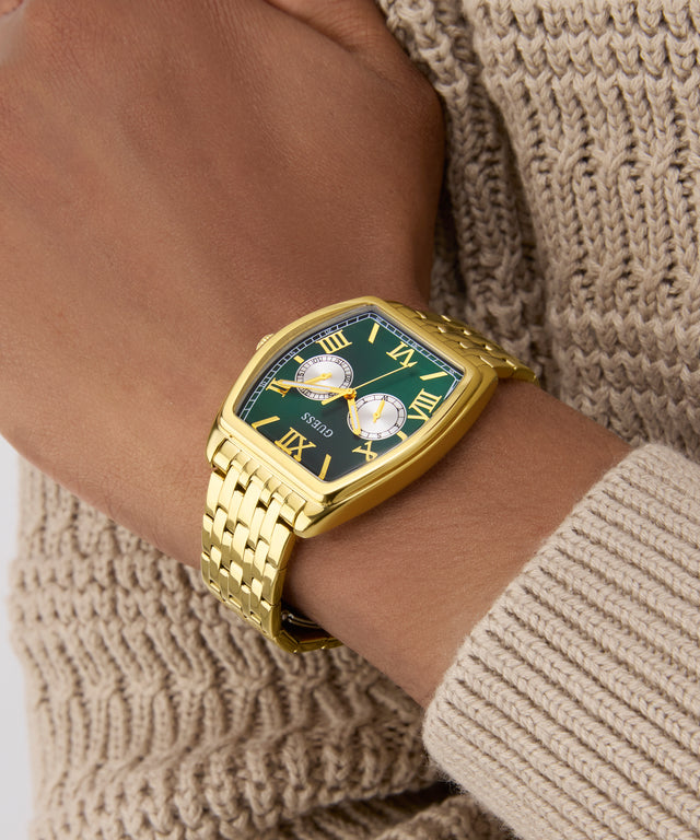 Gold wristwatch with a green face on a wrist wearing a beige sweater. GW0975G2