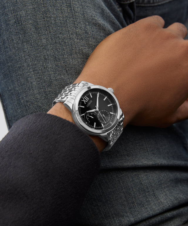 Silver GUESS Mens Silver Tone Multi-function Watch on a person's wrist with a dark background