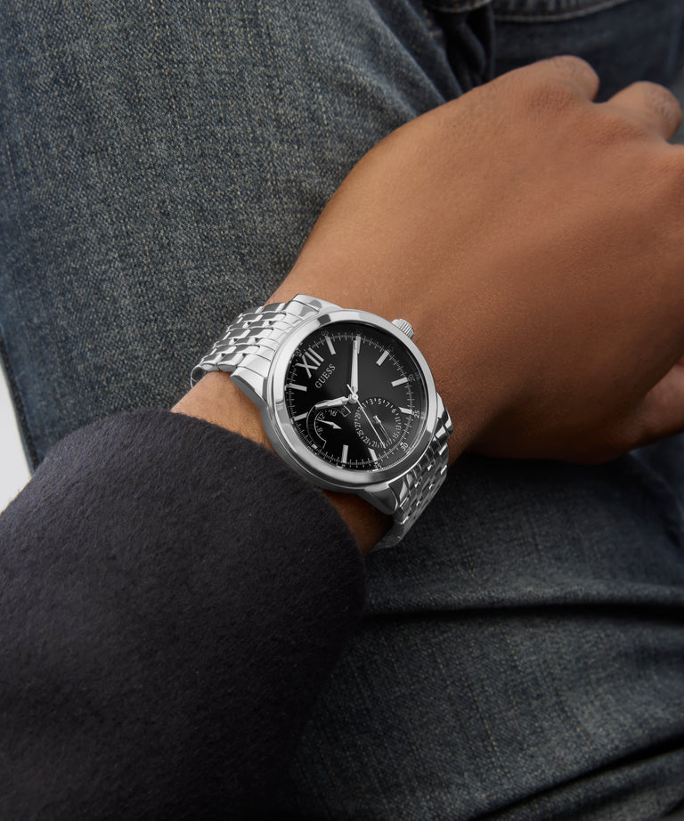 Silver GUESS Mens Silver Tone Multi-function Watch on a person's wrist with a dark background