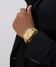 GUESS Mens Gold Tone Multi-function Date Watchon a person wearing a black suit against a light gray background