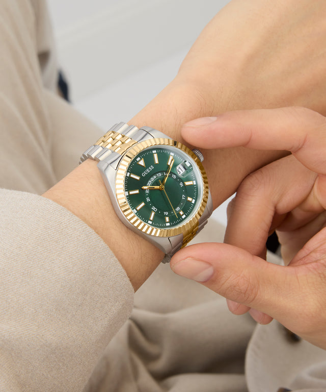 Close-up of a wrist wearing a two-tone watch with a green face. GW0977G4