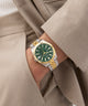 Gold and silver watch with green face on a wrist wearing a beige suit. GW0977G4