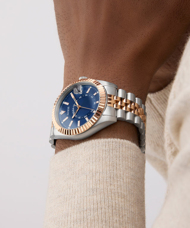 Luxury watch with blue dial and rose gold accents on a wrist against a neutral background GW0977G5