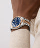 Luxury watch with blue dial and rose gold accents on a wrist against a neutral background GW0977G5