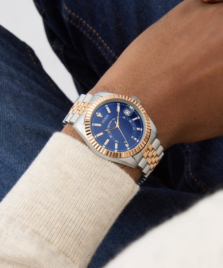 Wrist wearing a two-tone watch with a blue face, close-up on a neutral background GW0977G5