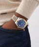 Close-up of a wrist wearing a silver and rose gold watch with a blue face. GW0977G5