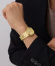 GUESS Mens Gold Tone Date Watch on a person's wrist with a neutral background