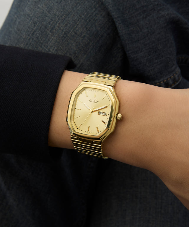 Gold watch on a wrist with a dark background