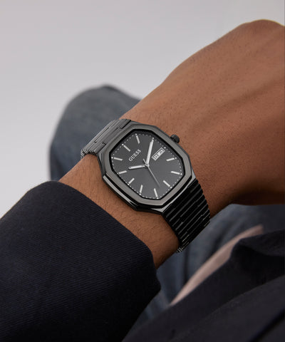 GUESS Mens Black Date Watch on a wrist with a neutral background